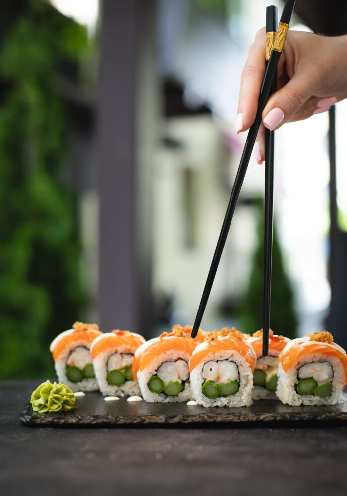 hand-holding-pair-chopsticks-holding-sushi-roll hand-holding-pair-chopsticks-holding-sushi-roll